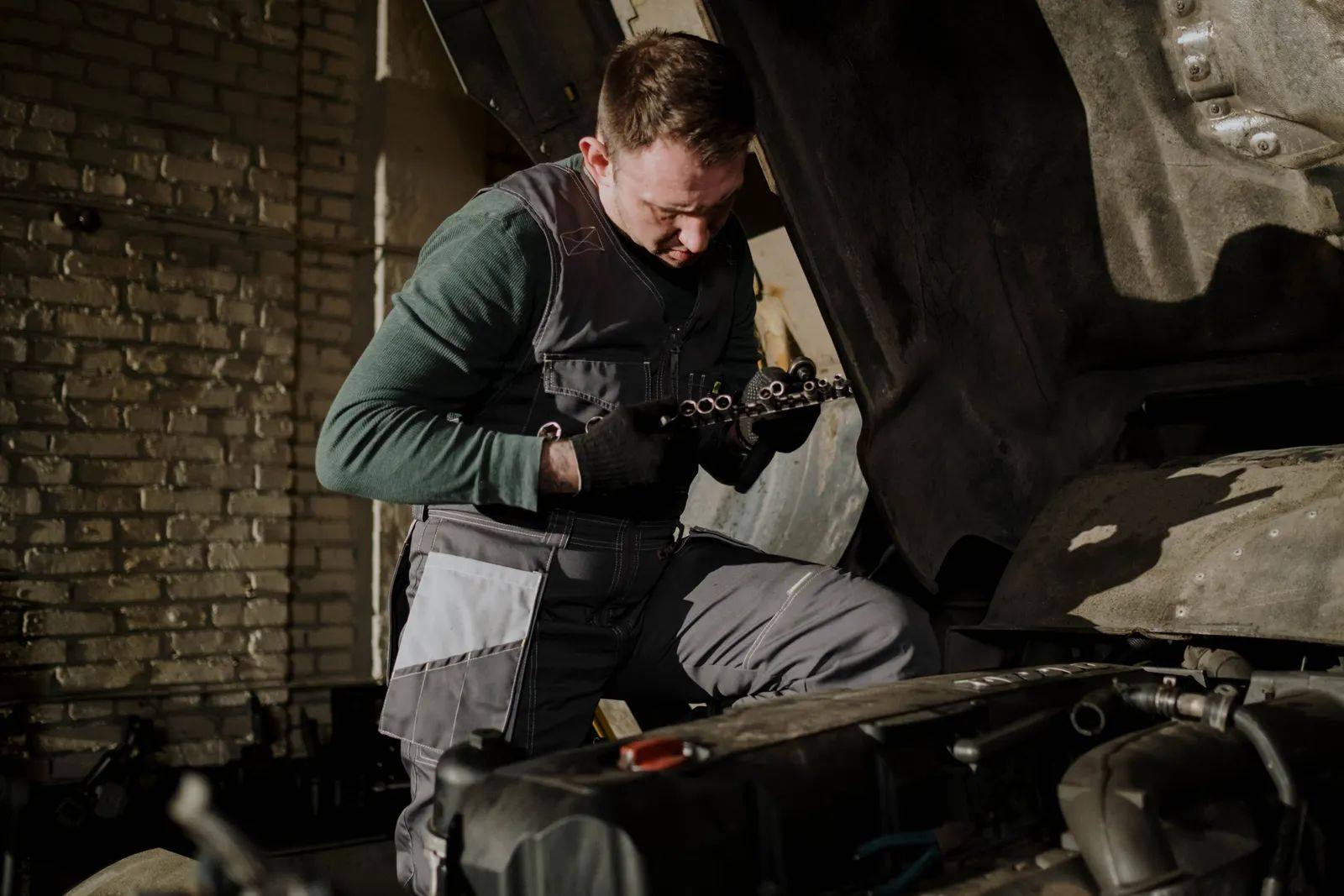 Heartland Auto Group technician with a part beside an open engine